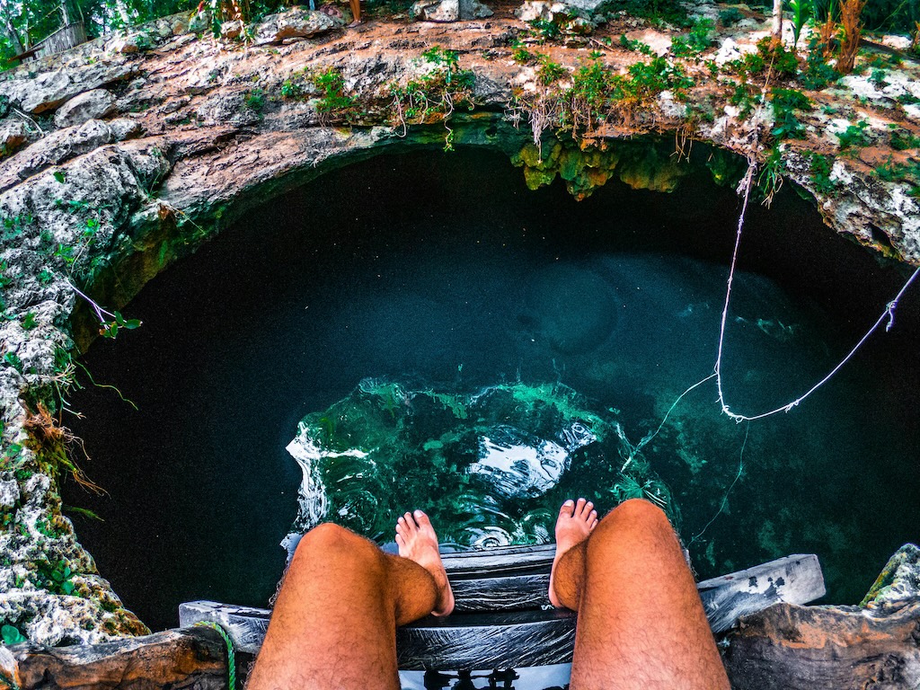 Tulum, QR, México. Persona sentada en una escalera con vista al agua subterránea